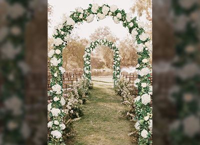 immagine di una camminata per sposalizio allestita con archi di ghirlanda e rose